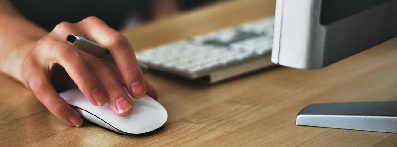 A close up of a woman's hand with her hand on the mouse of a computer